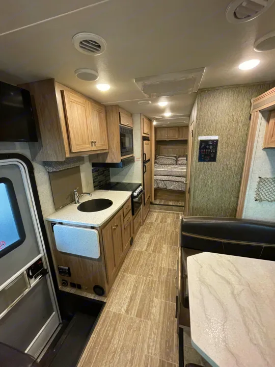 Explore this RV rental's modern interior: full kitchen, dinette, and comfortable rear bedroom. Perfect for travel.. Forest River Sunseeker 2018