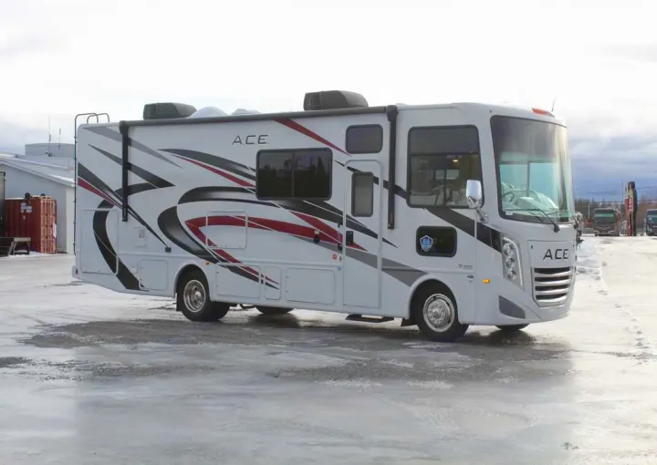 A white ACE Class A RV with black and red decals, available for rv rental, parked on a snowy surface.. Thor Motor Coach ACE 29D 2023