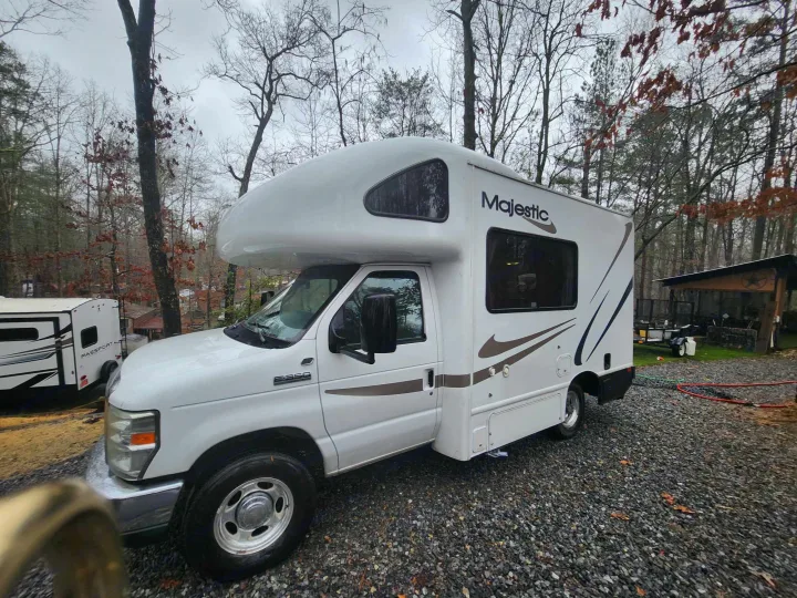 Majestic Ford E-350 Class C RV rental parked on gravel amid trees; ready for your outdoor adventure.. Thor 2012 Thor 19G 2012