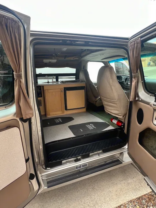 Interior of an RV rental: a cozy camper van with a compact kitchen, front seats, and safety gear.. Ford Pleasure Way Xl Rd Widebody 2002
