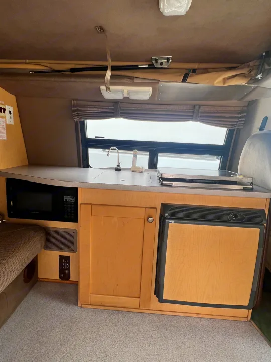 Well-equipped RV rental galley kitchen with microwave, refrigerator, sink, and stovetop, perfect for on-the-go meals.. Ford Pleasure Way Xl Rd Widebody 2002