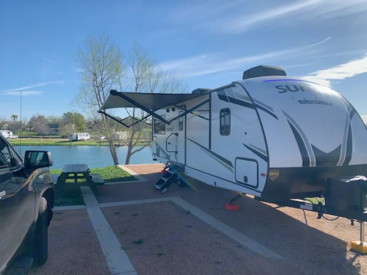 RV rental parked at a serene waterfront campsite with a picnic table, ready for a relaxing vacation.. Crossroads RV Sunset Trail Super Lite 2022
