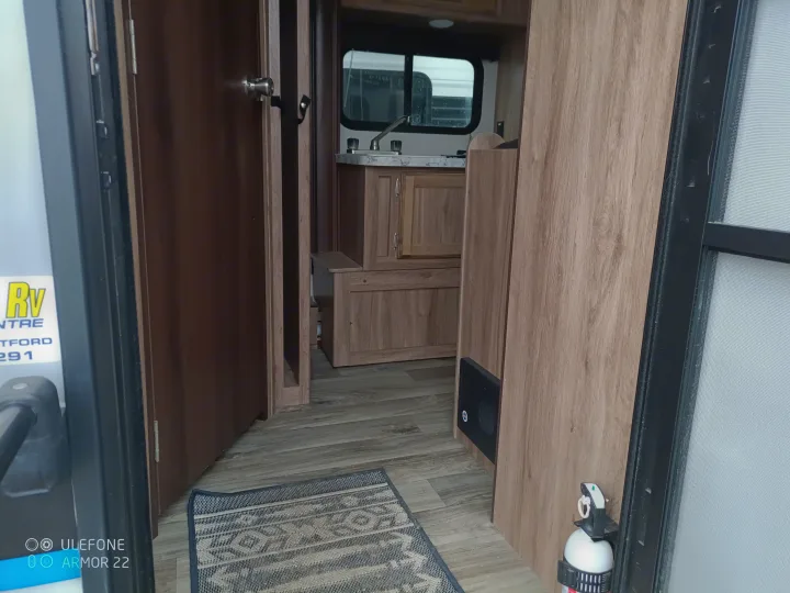 Looking into an RV rental from the door, featuring a kitchen area, a closed interior door, and a fire extinguisher.. Jayco Hummingbird 2018