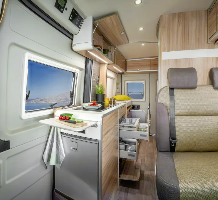 This rv rental interior features a modern kitchenette with a stunning sea view, ample storage, and comfortable seating, ready for travel.. Hymer Ayers Rock 2024