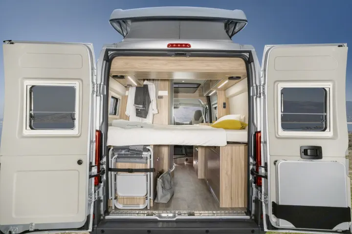 Rear view of a spacious RV rental interior with bed, storage, and open doors showing a scenic landscape.. Hymer Ayers Rock 2024