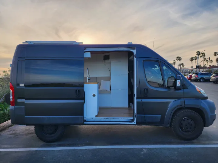 Modern dark grey camper van with open door revealing a stylish, functional interior. Perfect for your next rv rental trip!. Dodge Sprinter Van 2015