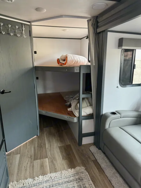 RV rental: A cozy sleeping and living area with bunk beds, a sofa with a cup holder, and wood-look flooring.. Keystone RV Bullet Crossfire 2022