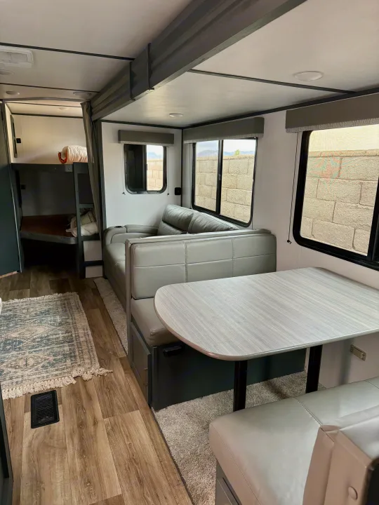 Inside a modern rv rental, featuring a light gray dinette, sofa, and bunk beds, offering a comfortable, inviting living space.. Keystone RV Bullet Crossfire 2022