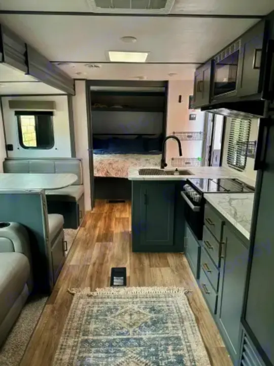RV rental interior: modern kitchen, dining booth, and bunk beds visible. Light wood-look flooring with a rug. Spacious design.. Keystone RV Bullet Crossfire 2022