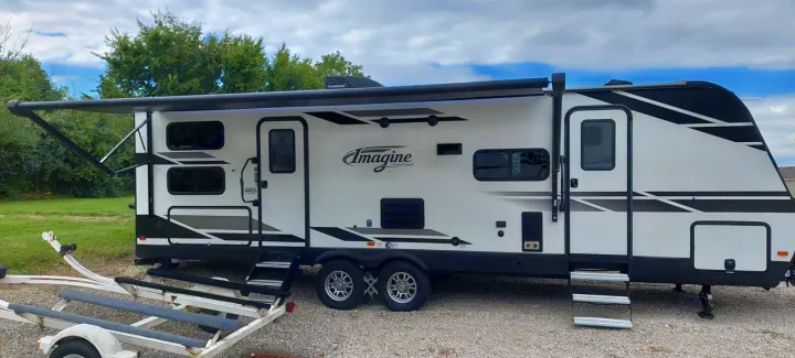 This white Imagine travel trailer RV rental features an extended awning & comfortable steps, ideal for outdoor adventures.. Grand Design Imagine 2021
