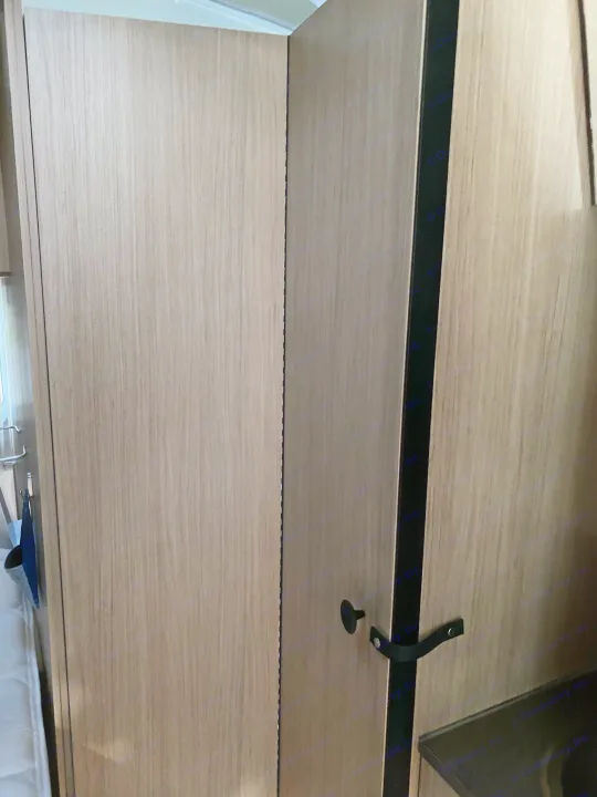 RV rental: Light wood-grain interior showing cabinet doors with a black vertical trim and a securing latch. Practical RV storage.. Airstream Flying Cloud 2018