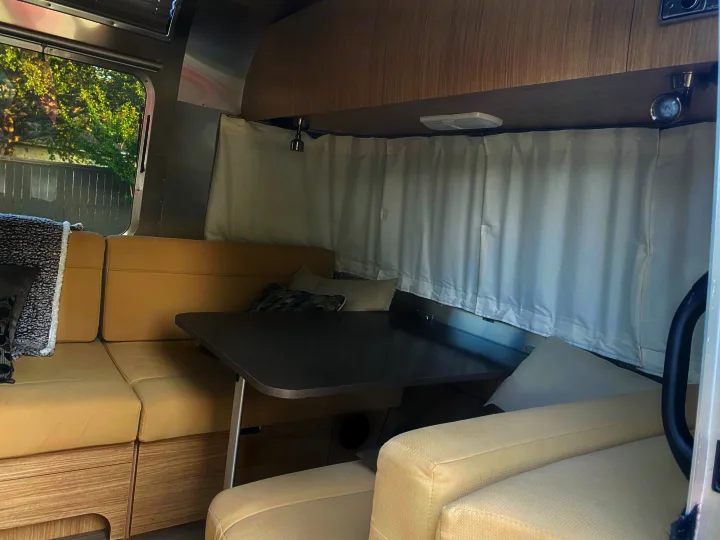 Experience comfort in this RV rental! Spacious travel trailer dinette with beige seating, table, and windows for scenic views.. Airstream Flying Cloud 2018