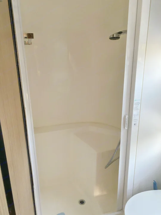 Compact Nautilus shower stall in an RV rental. Features a handheld shower and drain, ideal for travel.. Airstream Flying Cloud 2018
