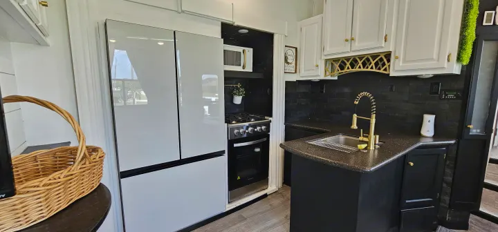 Sleek RV rental kitchen design: white fridge, black backsplash, dark counters, and gold faucet. Ready for adventure!. Heartland Edge 2016