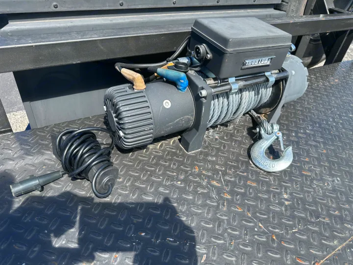 Powerful electric winch, vital for rv rental recovery. Features steel cable, hook, and remote control cable on diamond plate.. East Texas Trailers Car Hauler 2021