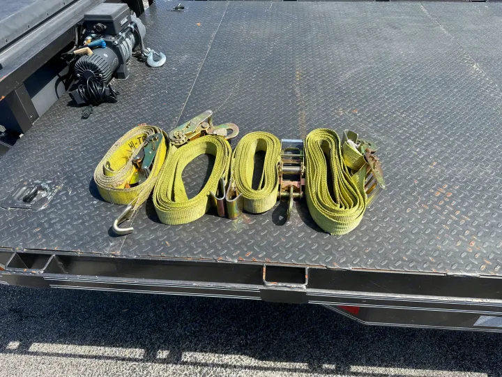 Trailer bed and winch, with multiple tie-down straps coiled and ready for securing cargo, for an RV rental.. East Texas Trailers Car Hauler 2021