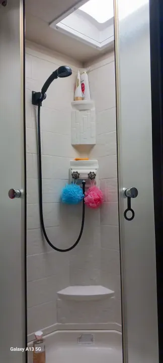 RV rental shower: View of a compact, white-tiled shower with handheld spray, toiletries, and colorful sponges.. Forest River Salem Cruise Lite 2018