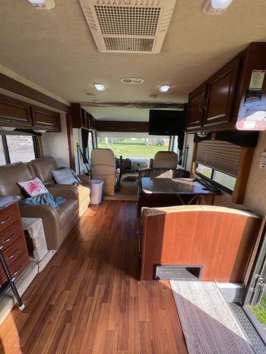 Spacious RV rental interior: a bright living area with a comfy sofa, dining table, and driver's cockpit.. Storm Storm Motorhome 2011