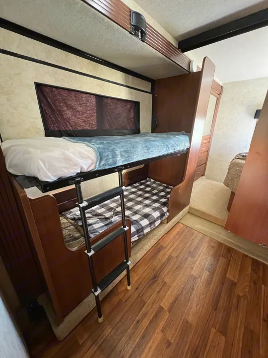 Cozy RV rental interior featuring spacious bunk beds, perfect for family adventures on the road. Includes ladder access to upper bunk.. Storm Storm Motorhome 2011