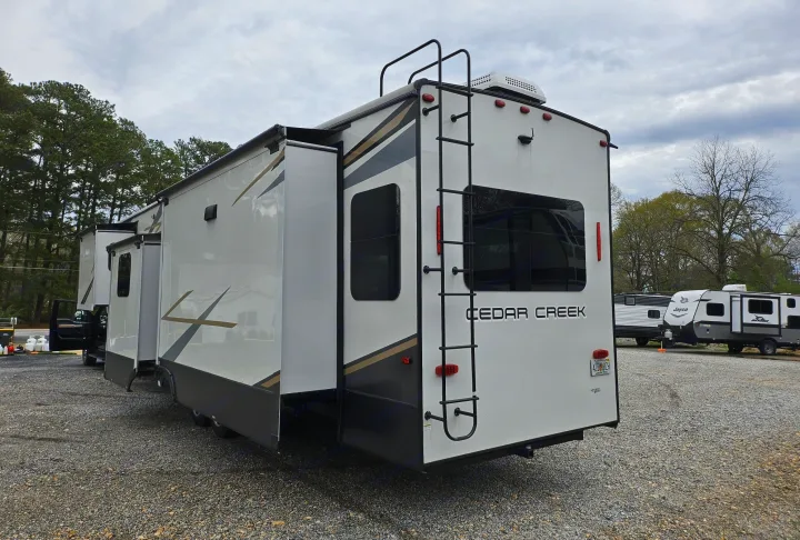 Explore the outdoors with this large Cedar Creek fifth-wheel RV rental, parked on gravel with slides out.. Forest River Cedar Creek Fifth Wheel 2022