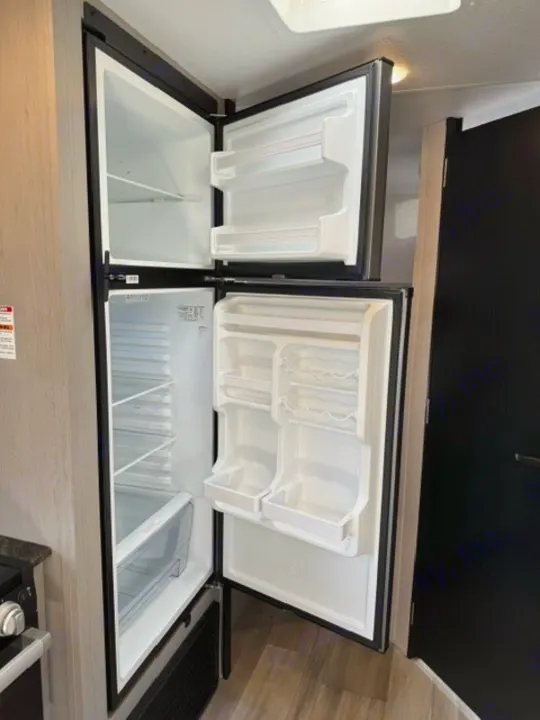 Clean, open refrigerator interior in an RV rental, showing empty shelves and door compartments.. Forest River Tracer 2022