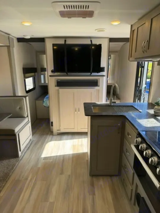 Interior view of a modern RV rental featuring a kitchen, dinette, and entertainment center with TV.. Forest River Tracer 2022