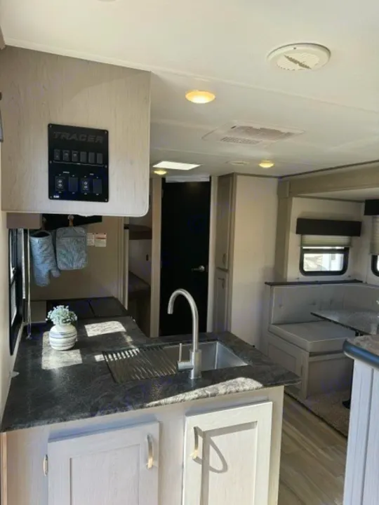 Spacious and bright RV rental interior. Features a modern kitchen, comfortable dining area, and essential control panel.. Forest River Tracer 2022