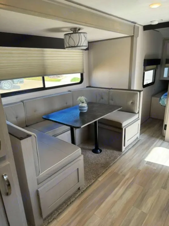Cozy RV rental dinette setup with plush gray seating, a table, and light wood-look floors. Ideal for your next adventure.. Forest River Tracer 2022