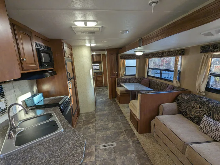 Step inside this RV rental's inviting interior: featuring a well-equipped kitchen, dining booth, and comfy living area.. Winnebago Sunset Creek 2014