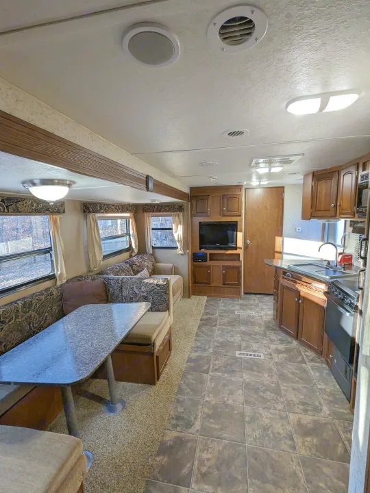 Spacious RV rental interior with dinette, kitchen, and living area, featuring tile and carpet flooring.. Winnebago Sunset Creek 2014