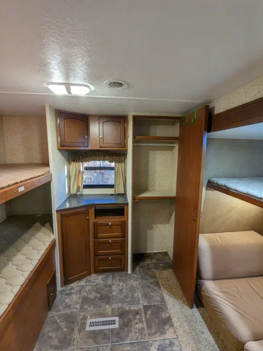 Spacious RV rental interior with comfortable bunk beds, ample storage cabinets, and a convenient wardrobe.. Winnebago Sunset Creek 2014