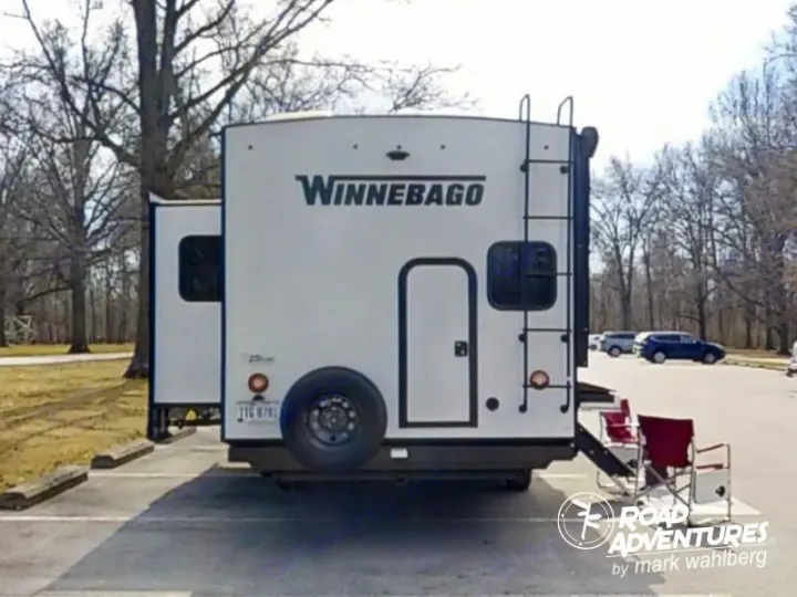 This Winnebago rv rental travel trailer is parked, slide-out extended, chairs ready for a scenic road trip adventure.. Winnebago Minnie 2801BHS 2024