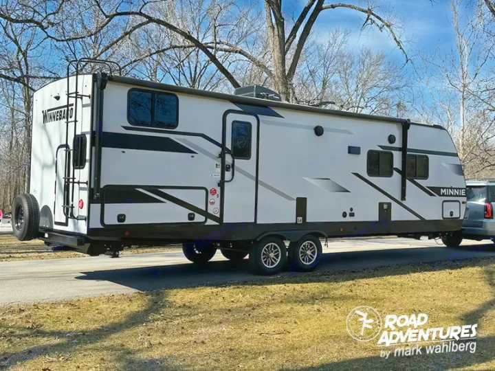 This white Winnebago Minnie travel trailer, ideal for an RV rental adventure, is ready for camping and exploring nature.. Winnebago Minnie 2801BHS 2024