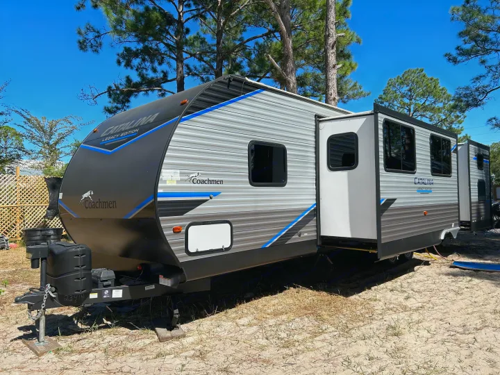Coachmen Catalina travel trailer (RV rental) at a sunny campsite with extended slide-out, ready for adventure.. Coachmen Catalina Legacy 2022