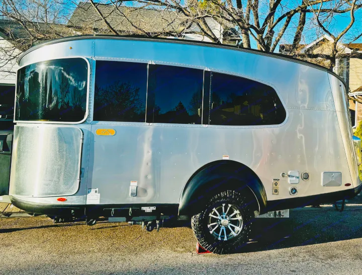 This sleek silver Airstream-style travel trailer, perfect for an rv rental adventure, is ready for outdoor travel.. Airstream Basecamp 2023