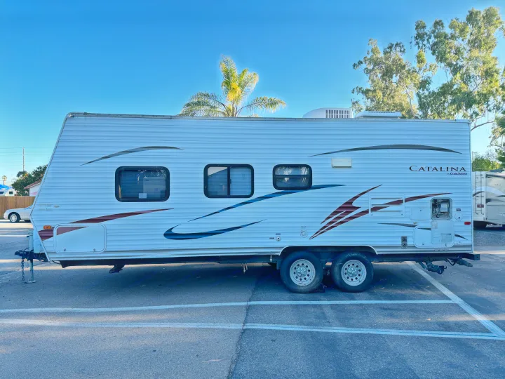 Side view of a white Catalina travel trailer (RV) parked on asphalt, available as an RV rental.. Coachmen Catalina 2010
