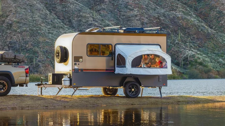 Family enjoys an RV rental camper by a lake, with a truck nearby. Ideal for scenic outdoor adventures.. InTech RV Flyer Discover 2021