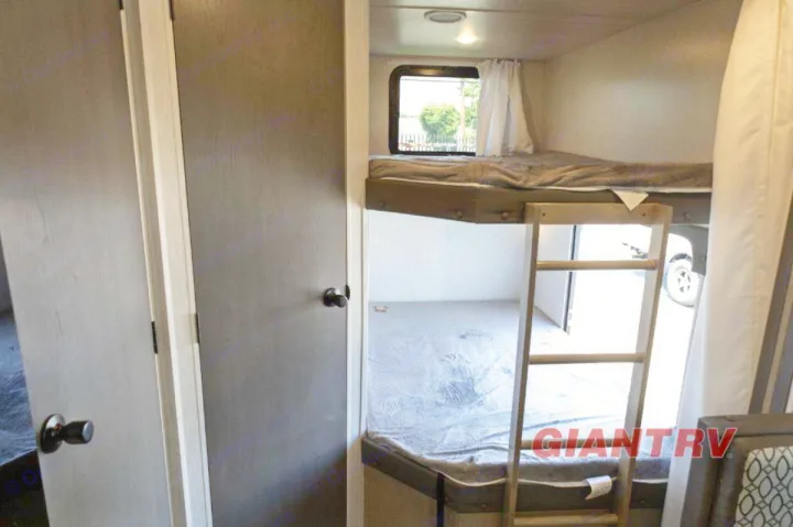 Inside a spacious RV rental, a bunk bed setup with a ladder and window offers comfortable sleeping for your camping adventures.. Forest River Evo CSJT2650G 2023