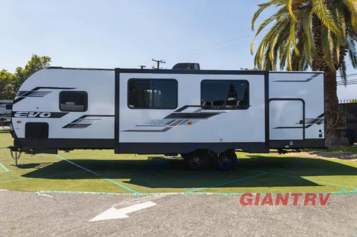 Side view of a white EVO travel trailer, a sleek RV rental with black accents, parked on grass.. Forest River Evo CSJT2650G 2023