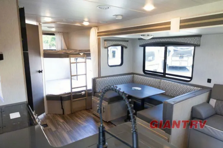 Bright RV rental interior featuring bunk beds, a U-shaped dinette, and kitchen for your next adventure.. Forest River Evo CSJT2650G 2023