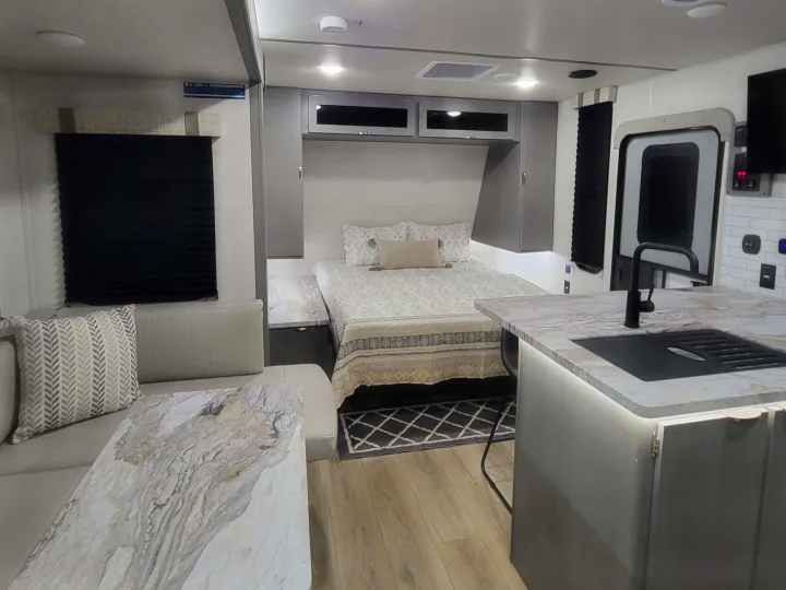 Modern rv rental interior showcasing a cozy bedroom, living space, and kitchen with sink, ideal for your next adventure.. Forest River ozark 2440bhkx 2024