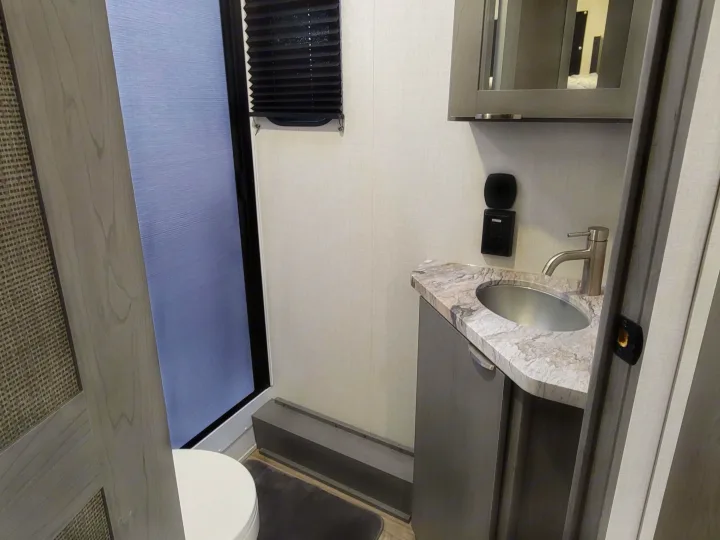 RV rental bathroom: A compact space with a shower, toilet, and a modern vanity with a silver sink and mirrored cabinet.. Forest River ozark 2440bhkx 2024