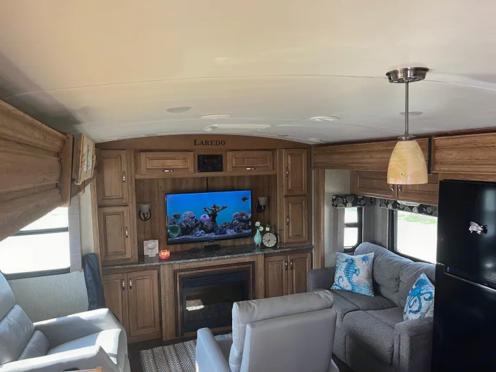 Spacious RV rental interior: living room with TV, fireplace, couch, and recliner. Cozy camper setup.. Keystone Laredo 2015