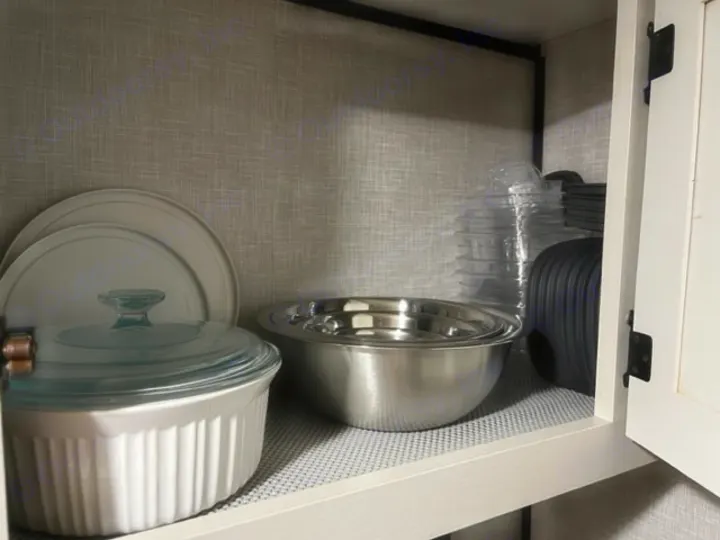 RV rental kitchenware in cabinet: plates, casserole dish, mixing bowls, and food storage containers.. Highland Ridge RV Open Range 2023
