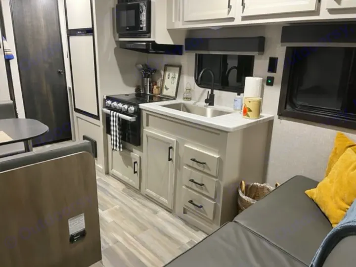 Comfortable RV rental interior featuring a well-equipped kitchen with stove & sink, dinette, and plush seating.. Highland Ridge RV Open Range 2023
