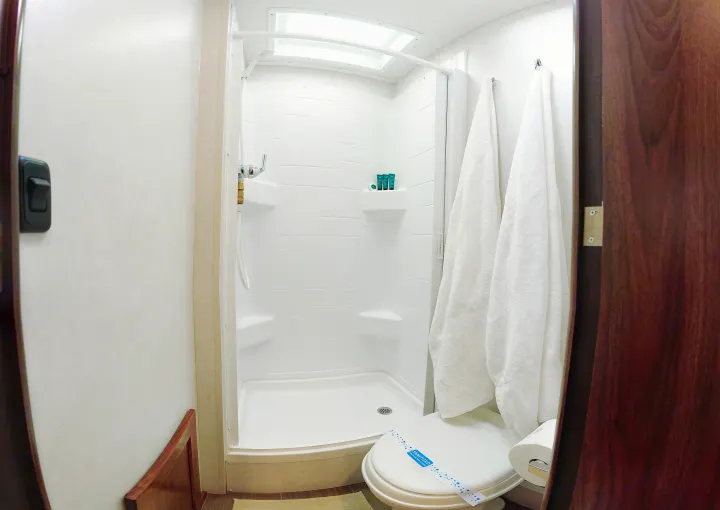 This clean RV rental bathroom features a compact shower, toilet with a "sanitized" band, and fresh towels.. Winnebago Vita 2020
