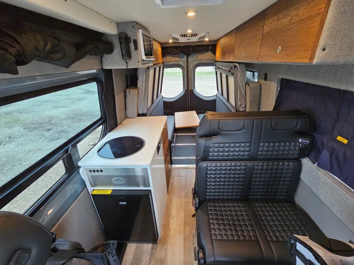 Explore this modern rv rental interior featuring a compact kitchen, plush seating, and storage, perfect for adventures.. Storyteller Overland Stealth Mode 2021