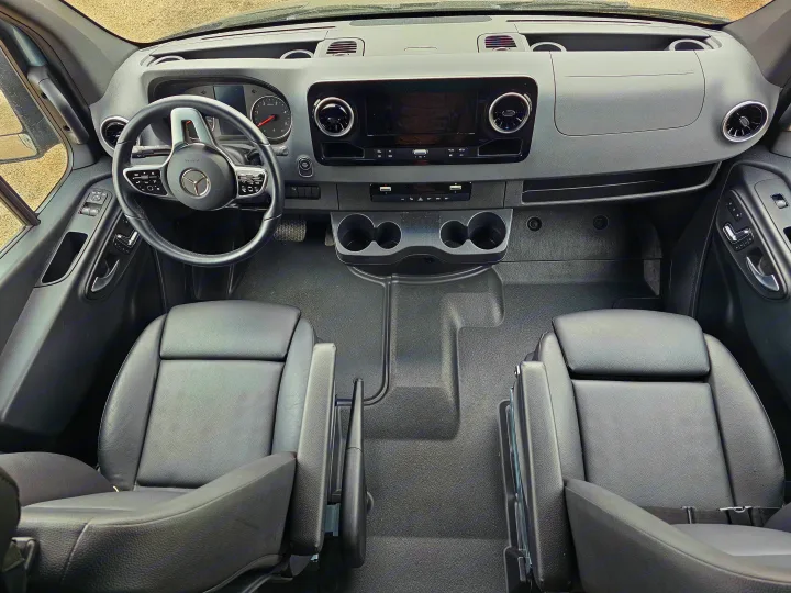 Modern rv rental van cockpit: dashboard, Mercedes steering wheel, infotainment, dual seats, and cup holders visible.. Storyteller Overland Stealth Mode 2021