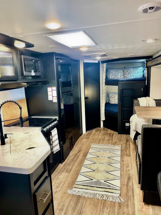 Explore this modern RV rental interior featuring a full kitchen, comfy bunk beds, and a cozy dinette. Perfect for your next adventure!. Forest River Cherokee Grey Wolf 2022