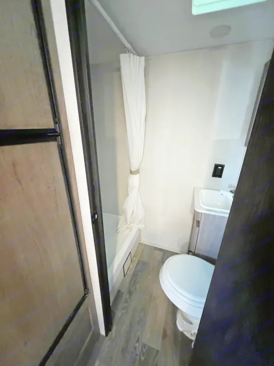 Step inside this RV rental's compact bathroom, featuring a shower, toilet, and sink area.. Keystone Hideout 2021